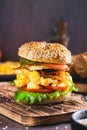 Homemade bagel with scramble egg, bacon, cheese, tomato and lettuce on a board vertical view Royalty Free Stock Photo