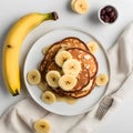 Homemade bake banana pancakes with topping fresh banana slices, walnuts and honey on whit plate, Top view