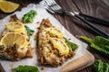 Baked pollock fillet with lemon and spinach on a wooden background