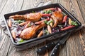 Homemade baked pork chops with red onions, herbs and rhubarb close-up in a baking sheet. Horizontal