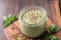 Homemade basil pesto sauce in a glass jar on a wooden board. Healthy food concept. Generative AI Royalty Free Stock Photo