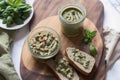 Homemade basil pesto sauce in a glass jar on a wooden board. Healthy food concept. Generative AI Royalty Free Stock Photo