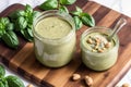 Homemade basil pesto sauce in a glass jar on a wooden board. Healthy food concept. Generative AI Royalty Free Stock Photo