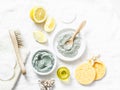 Homemade beauty facial mask. Clay, lemon, oil, facial brush - beauty products ingredients on light background