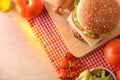 Homemade burger on cutting board with ingredients on wood table Royalty Free Stock Photo