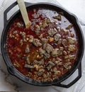 Homemade beef Chili in a rich savory sauce with onions, corn, beans, steak, and carrots in a cast iron pot Royalty Free Stock Photo