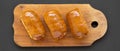 Homemade beef sausage kolache on a rustic wooden board on a black surface, overhead view. Flat lay, top view, from above Royalty Free Stock Photo