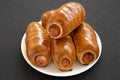 Homemade beef sausage kolache on a white plate on a black surface, side view. Close-up