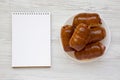 Homemade beef sausage kolache on a white plate, blank sheet of paper on a white wooden background, top view. Copy space