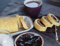 Homemade biscuit sponge roll with sweet plum jam and tea against a dark background. Natural homemade dessert, side view Royalty Free Stock Photo