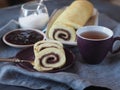 Homemade biscuit sponge roll with sweet plum jam and tea against a dark background. Natural homemade dessert, side view Royalty Free Stock Photo