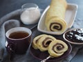 Homemade biscuit sponge roll with sweet plum jam and tea against a dark background. Natural homemade dessert, side view Royalty Free Stock Photo