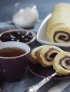 Homemade biscuit sponge roll with sweet plum jam and tea against a dark background. Natural homemade dessert, side view Royalty Free Stock Photo