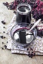 Homemade black elderberry syrup in glass bowl and jar