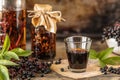 Homemade black elderberry syrup recipe in a glass bottle on a wooden table. Fresh berries in the background. Copy space Royalty Free Stock Photo