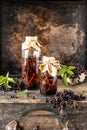 Homemade black elderberry syrup recipe in a glass bottle on a wooden table. Fresh berries in the background. Copy space Royalty Free Stock Photo