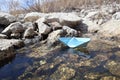 A homemade blue paper boat was launched into a stream with stones Royalty Free Stock Photo