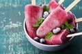 Homemade blueberry ice cream or popsicles decorated green mint leaves on teal rustic table, frozen fruit juice