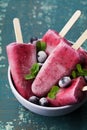 Homemade blueberry ice cream or popsicles decorated green mint leaves on teal rustic table, frozen fruit juice