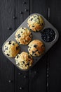 Homemade blueberry muffins and raw blueberries on black background with natural lighting top view Royalty Free Stock Photo