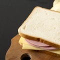 Homemade Bologna and Cheese Sandwich on a rustic wooden board on a black background, side view. Copy space