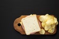 Homemade Bologna and Cheese Sandwich on a rustic wooden board on a black surface, top view. Copy space