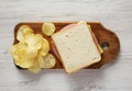 Homemade Bologna and Cheese Sandwich on a rustic wooden board on a white wooden background, overhead view. Flat lay, top view,