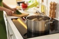 Homemade bouillon recipe. Woman cutting greenery in kitchen, focus on pot Royalty Free Stock Photo