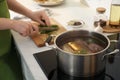 Homemade bouillon recipe. Woman cutting greenery in kitchen, focus on pot Royalty Free Stock Photo