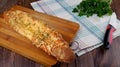 Homemade bread - baguette with cheese on top on a cutting board on a white towel Royalty Free Stock Photo