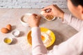 Homemade bread baking. closeup woman hands adding egg in flour, dough preparation in bright kitchen with marble countertop Royalty Free Stock Photo