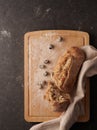 Homemade bread with black olives broken on a wooden chopping board and black olives, flour and decorative towel Royalty Free Stock Photo