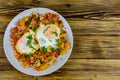 Homemade breakfast shakshuka with fried eggs, onion, bell pepper, tomatoes and dill on a wooden table. Jewish cuisine. Top view Royalty Free Stock Photo