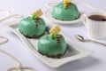 Homemade bright mousse cakes Hearts with green mirror icing on a white background, horizontal orientation