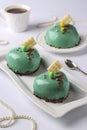 Homemade bright mousse cakes Hearts with green mirror icing on a white background, vertical orientation