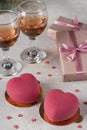 Homemade bright mousse cakes Hearts with pink velvet coating and two glasses of rose wine for Valentines Day