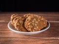 homemade brown oatmeal cookies in a white ceramic plate on a wood close-up