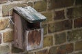 Homemade brown wooden bird box with a nest inside hanging on a brown bricked garden wall in summer Royalty Free Stock Photo