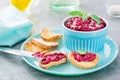 Homemade bruschetta with beetroot hummus on small toast on a plate and a table knife on the table