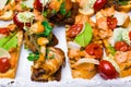 bruschetta with honey agaric, pesto, bacon, salad leafs, tomatoes, cream on white table Royalty Free Stock Photo