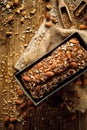 Homemade buckwheat bread with the addition of nuts and seeds in a baking tin on a wooden table, top view.