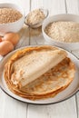 Homemade buckwheat crepes on a plate with ingredients. Vertical