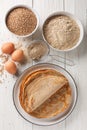 Homemade buckwheat crepes on a plate with ingredients. Vertical top view