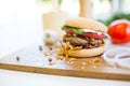 Homemade burger with beef, fried bacon and onion on wooden cutting board