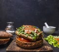 Homemade burger with chicken in mustard sauce, arugula, tomatoes on a cutting board on wooden rustic background top view close up Royalty Free Stock Photo