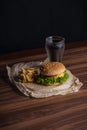 Homemade burger and french fries with oregano and frozen glass a tasty soda. Humburger served on pergament paper and wooden board.