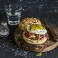 Homemade burger with fried egg and coleslaw on rustic wooden board on a dark stone background. Royalty Free Stock Photo