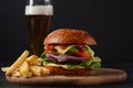 Homemade burger with grilled beef, cheese, onion, tomato, and green salad, sauce, with pickles and French fries, Royalty Free Stock Photo