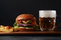 Homemade burger with grilled beef, cheese, onion, tomato, and green salad, sauce, with pickles and French fries, Royalty Free Stock Photo