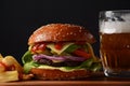 Homemade burger with grilled beef, cheese, onion, tomato, and green salad, sauce, with pickles and French fries Royalty Free Stock Photo